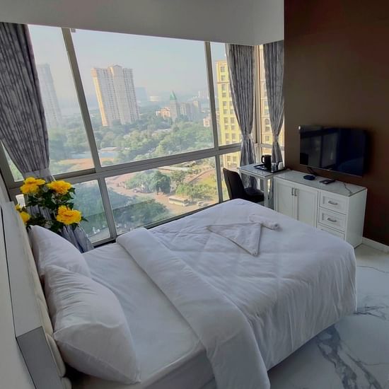 deluxe room at Maxxvalue Hotel, Chitranjan Tower, Powai with a posh bed and white linens along with floor-to-ceiling windows offering ciy view3