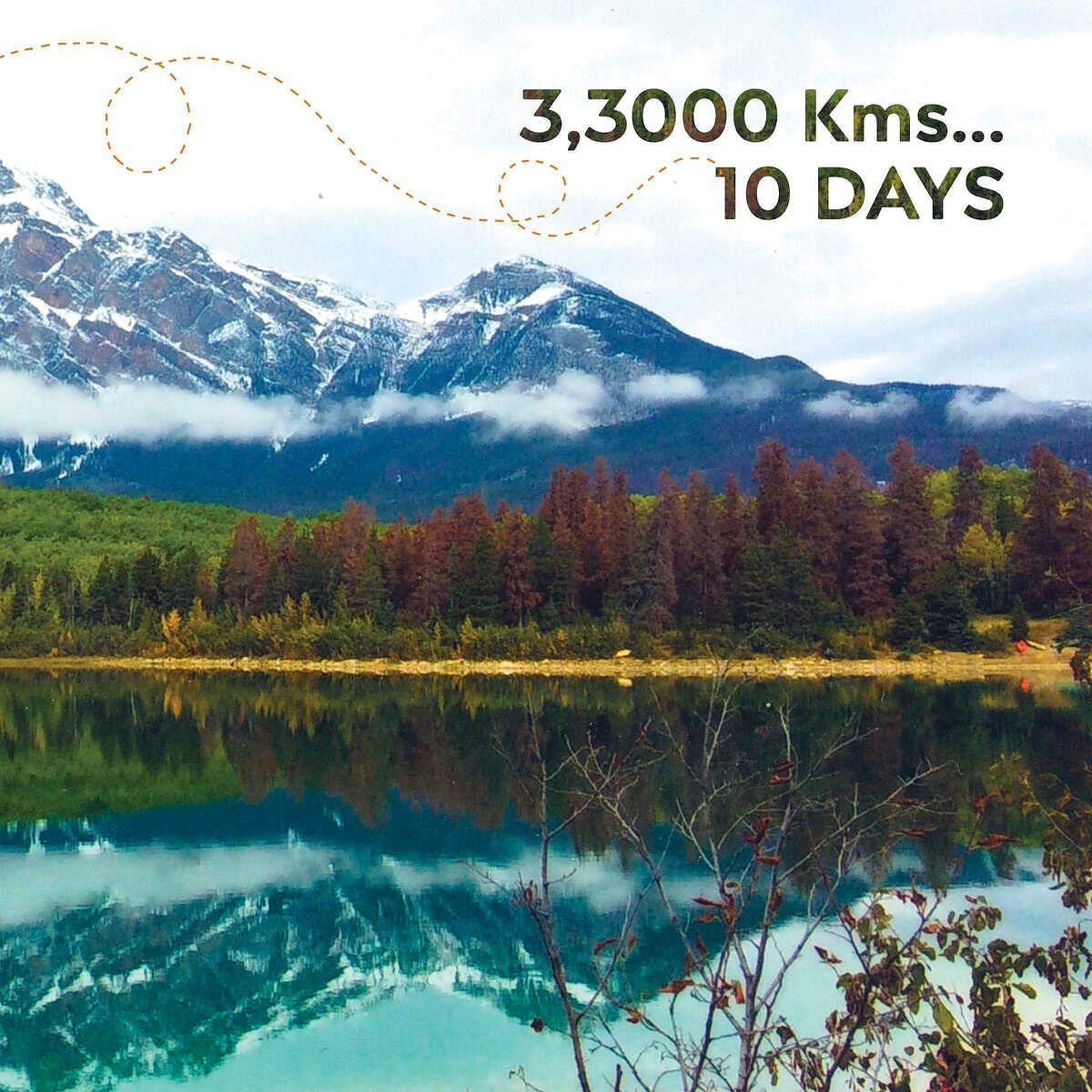 A view of a lake with red trees and snow topped mountains that reads 33000 kms 10 days. 