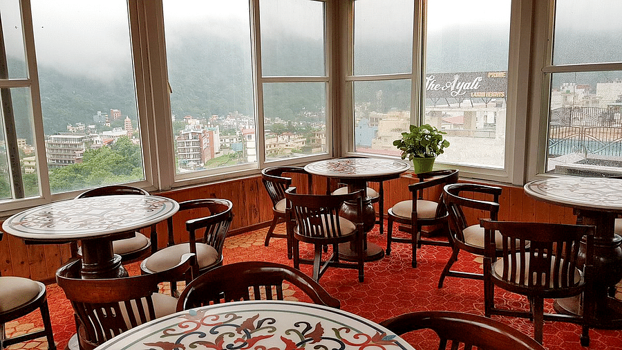 A close up shot of the restaurant with beautiful round dining table overlooking the city views from the window at Regenta Inn DLS.