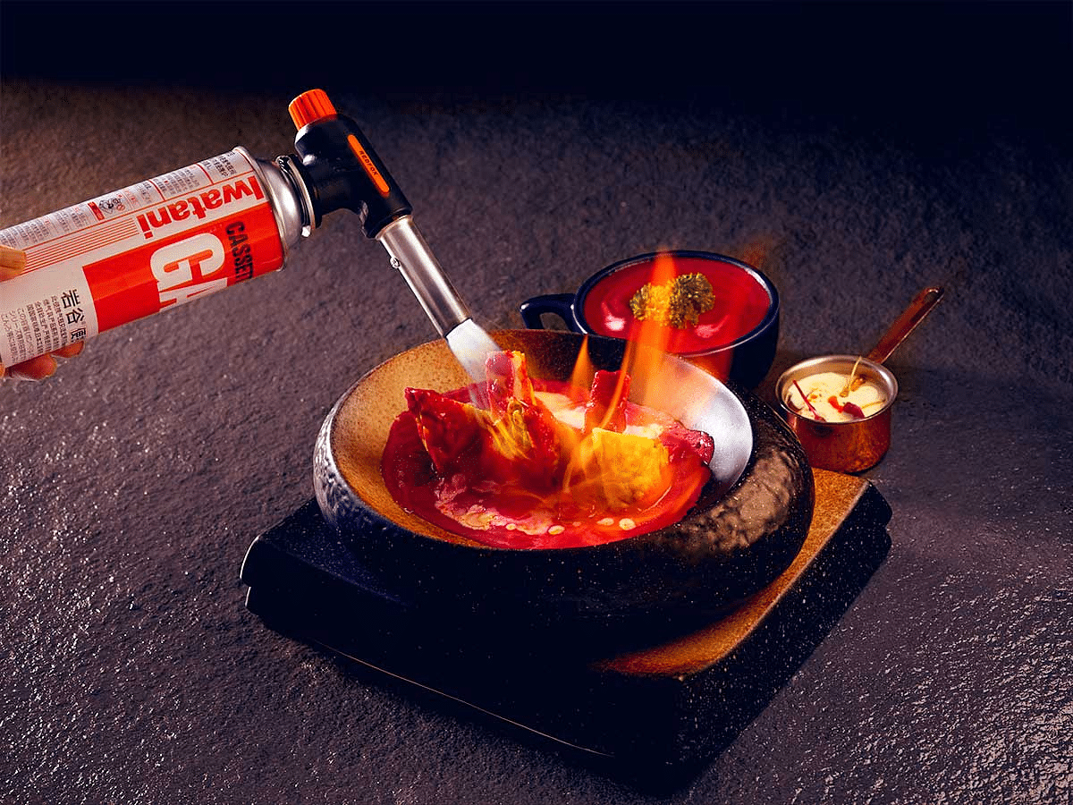 Dessert served with a syringe for flavour infusion, presented with a flaming effect.