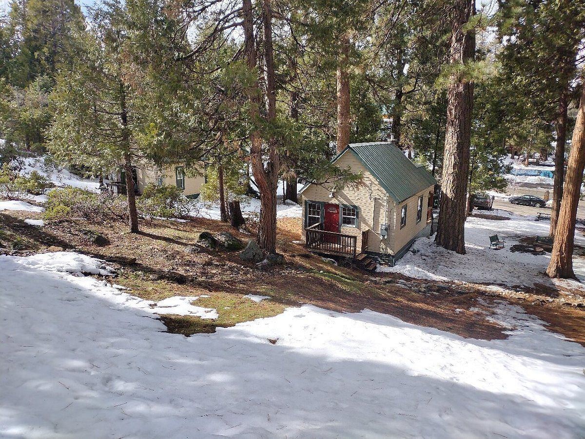 A sub-aerial view of the exterior of Shaver Lake Village Hotel surrounded by trees and fallen snow.
