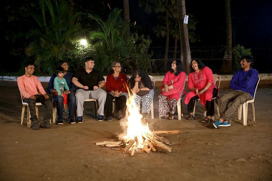 Campfire - Sajan - a group of 8 peopl sitting on chairs surrounding a camp fire and enjoying long talks.