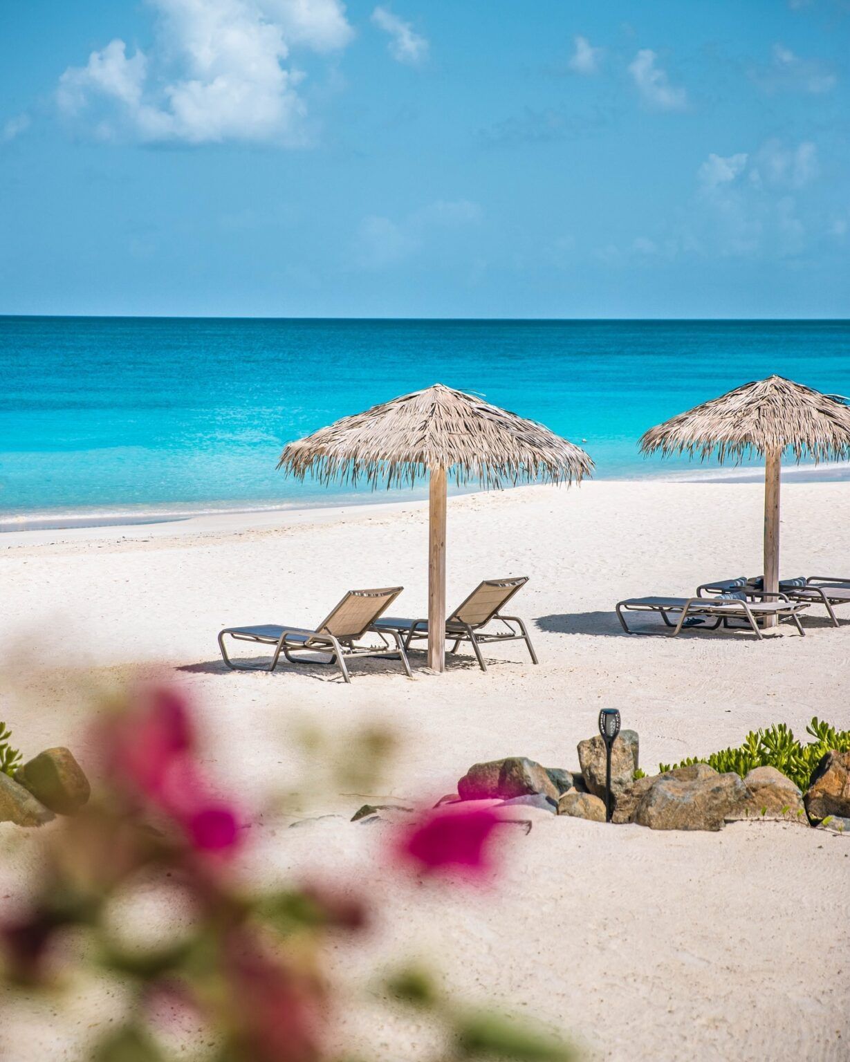 Sun loungers and straw umbrellas on the pristine beach near Tamarind Hills Antigua – Resort & Villas