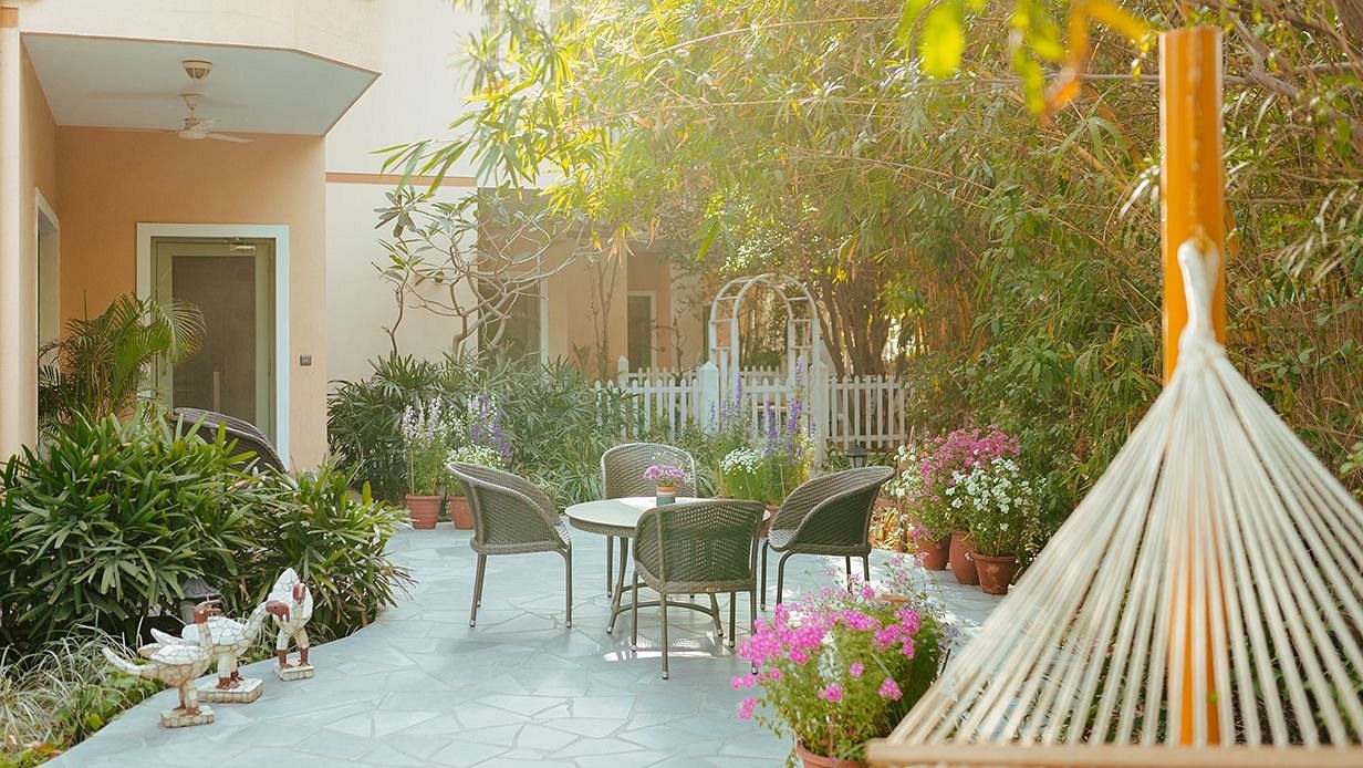 Outdoor seating at Karma Chalets with a hammock, round table, and plants surrounding a small courtyard.