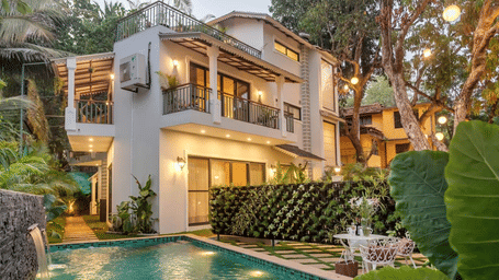 Villa exterior featuring a swimming pool, surrounding greenery, and evening lighting.