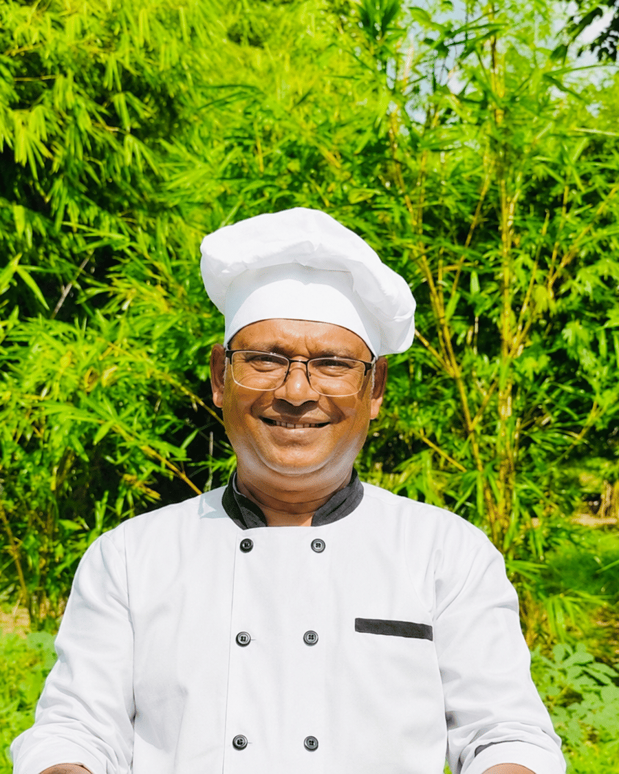 A chef of Signum Resort, Bandhavgarh in whites and toque, photographed against the resort's bamboo