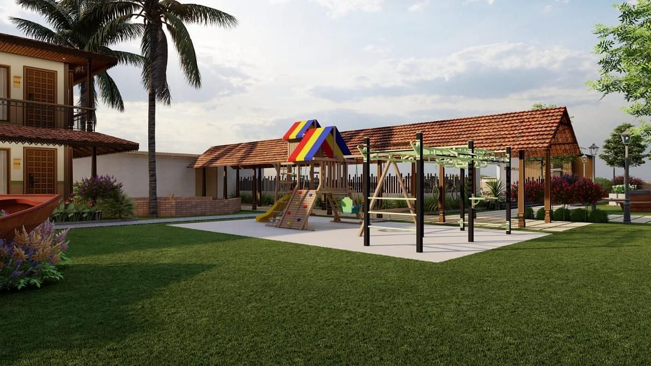 A grassy outdoor area with playground equipment and a building with a brown roof in the background, surrounded by trees and foliage.