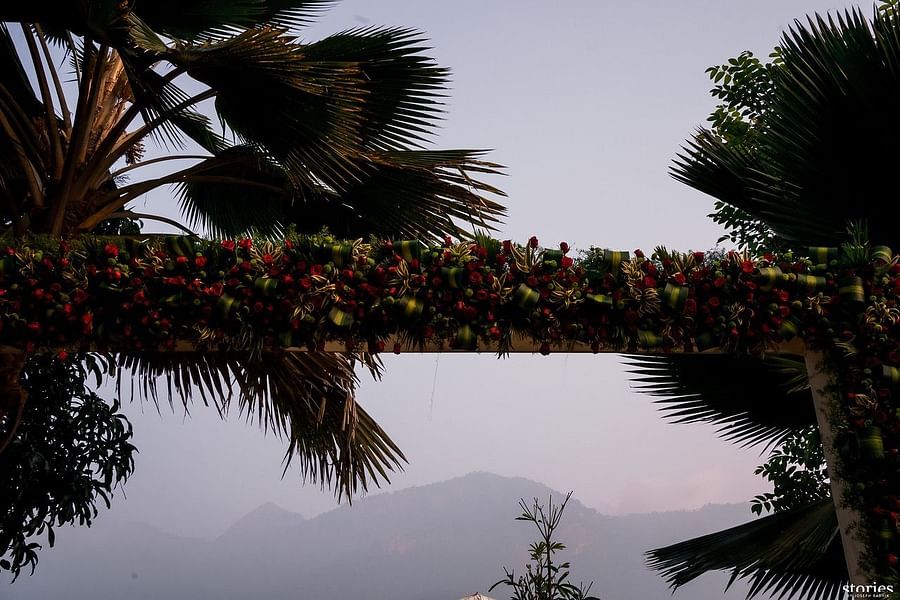 Floral archway adorned with vibrant flowers and greenery, creating a romantic entrance with palm trees in the background at Black Thunder, Coimbatore