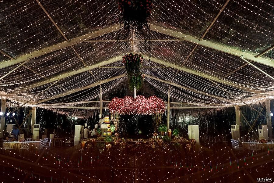 Spacious event hall with ceiling lights and hanging floral arrangements, featuring a central aisle leading to a stage at Black Thunder, Coimbatore