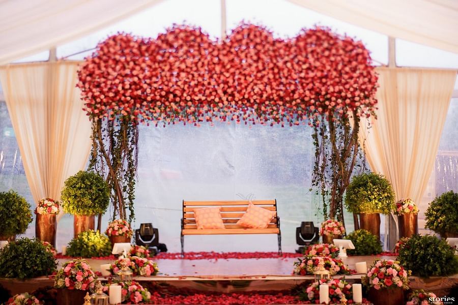 Beautifully decorated wedding stage with a floral arch in shades of pink and red, flanked by plants and flowers, set for a special ceremony at Black Thunder, Coimbatore