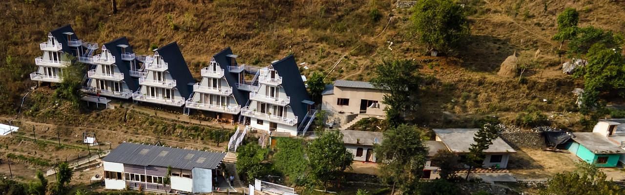 An overhead view of a group of modern, terraced buildings nestled on a sloping green hillside.