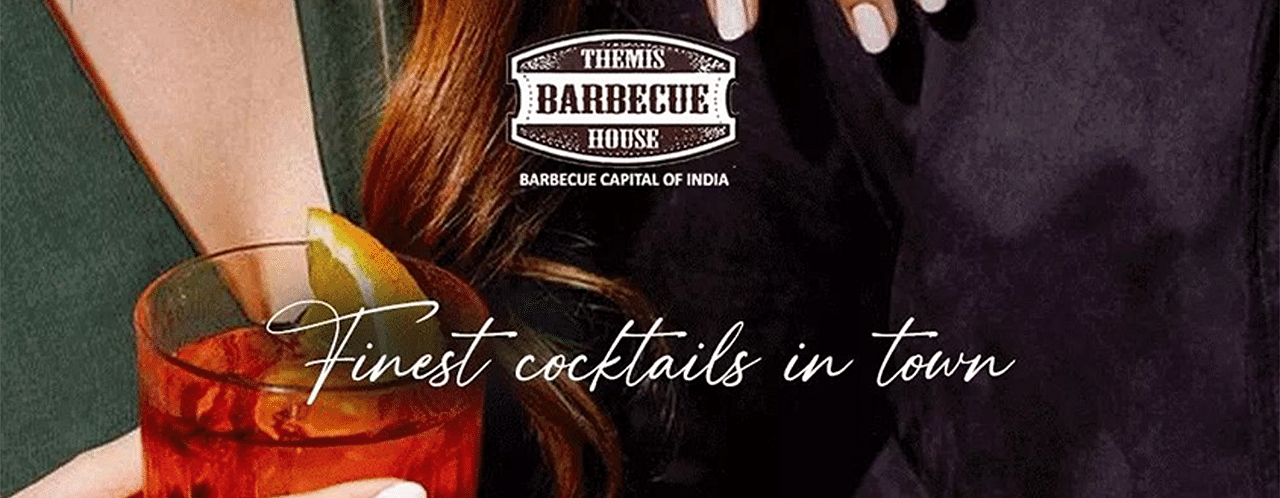 A creative image of a person holding a glass of cocktail  at Themis Barbecue House