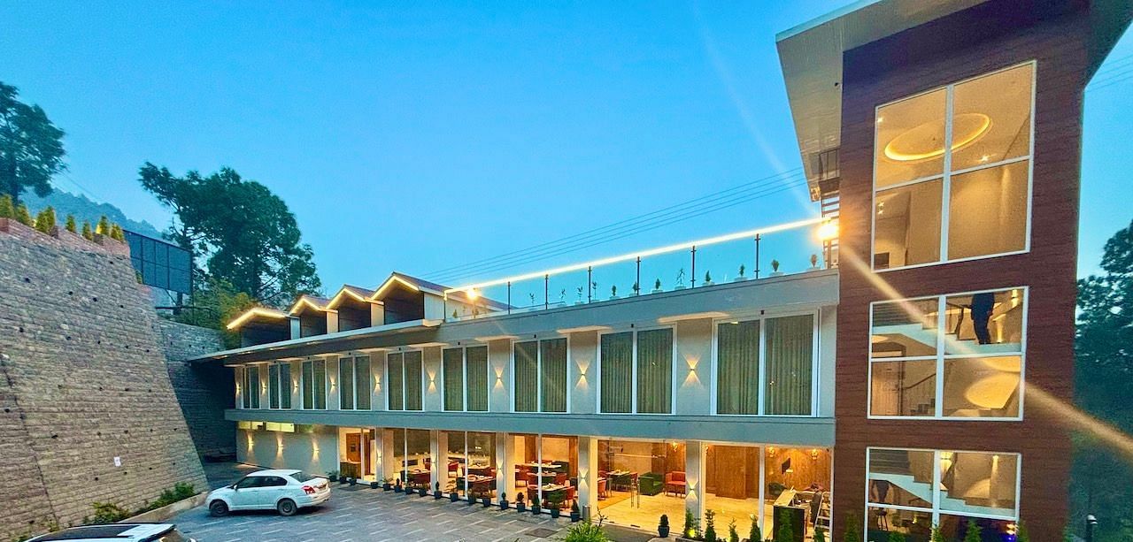 Exterior view of the ARNISA Boutique Hotel building with glass facade and neatly landscaped driveway