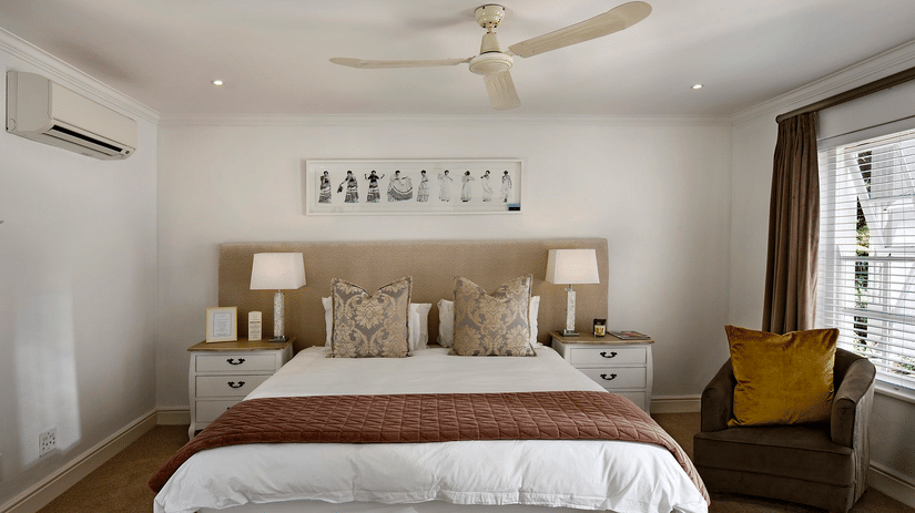 A double bed with a ceiling fan hanging over it in a bedroom.