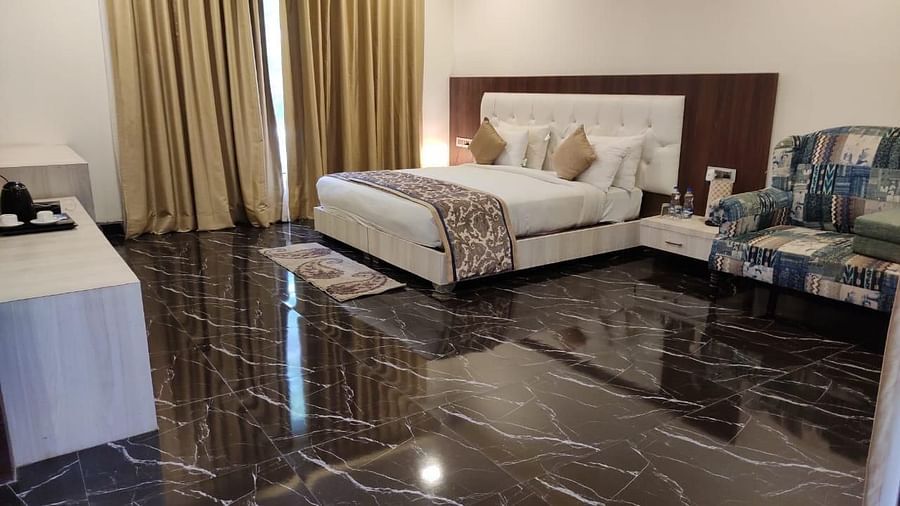 A room featuring a marble floor, a white bed, a sofa and  a storage unit  - Clarks Safari, Ranthambore