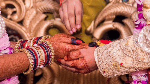 Close-up of the bride and groom exchanging wedding vows during a traditional ceremony, with intricate mehendi, floral garlands, and ceremonial rituals taking place | Clarks Amer, Jaipur