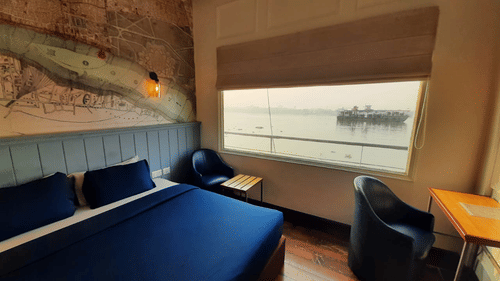 a bed with blue sheets beside a window 34 - polo floatel kolkata