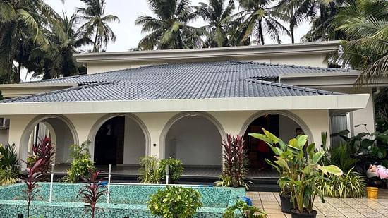 Facade view of Lamrin Morjim Goa, with arch design surrounded by trees.