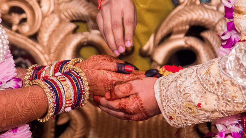 Close-up of the bride and groom exchanging wedding vows during a traditional ceremony, with intricate mehendi, floral garlands, and ceremonial rituals taking place | Clarks Amer, Jaipur