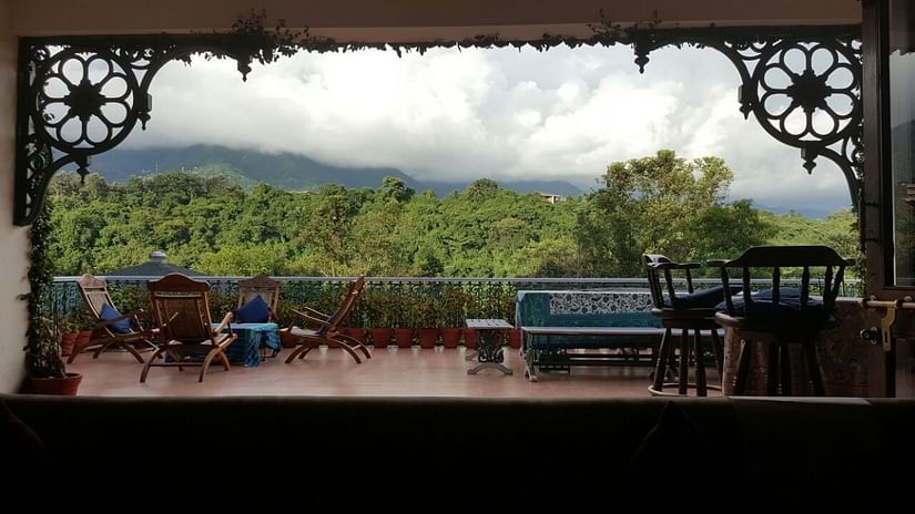 A scenic view of hills from a vintage balcony with wooden railings.