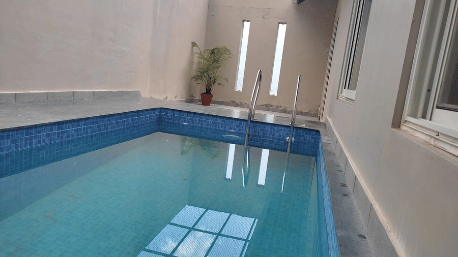 An indoor pool with a reflective surface shows the building's interior.- Abad Brookside Lakkidi, Wayanad