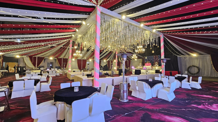 Lawn area at Ambrosia Sarovar Portico, Haridwar, elegantly decorated with draped fabric ceiling, chandeliers, round tables, and warm lighting.