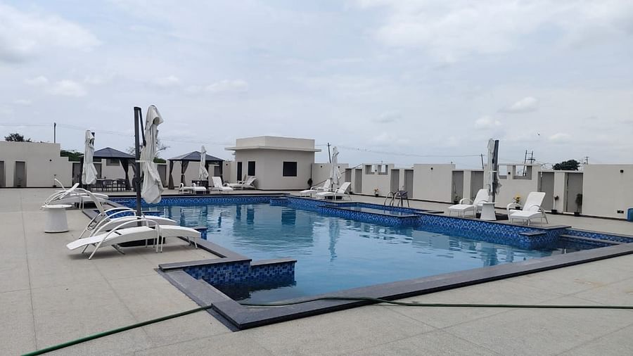 Rooftop swimming pool with tiled edges, surrounded by lounge chairs and closed umbrellas; cabanas in the background and a hose lying across the pool deck in the foreground under a partly cloudy sky - Kyriad Prestige, Ilkal