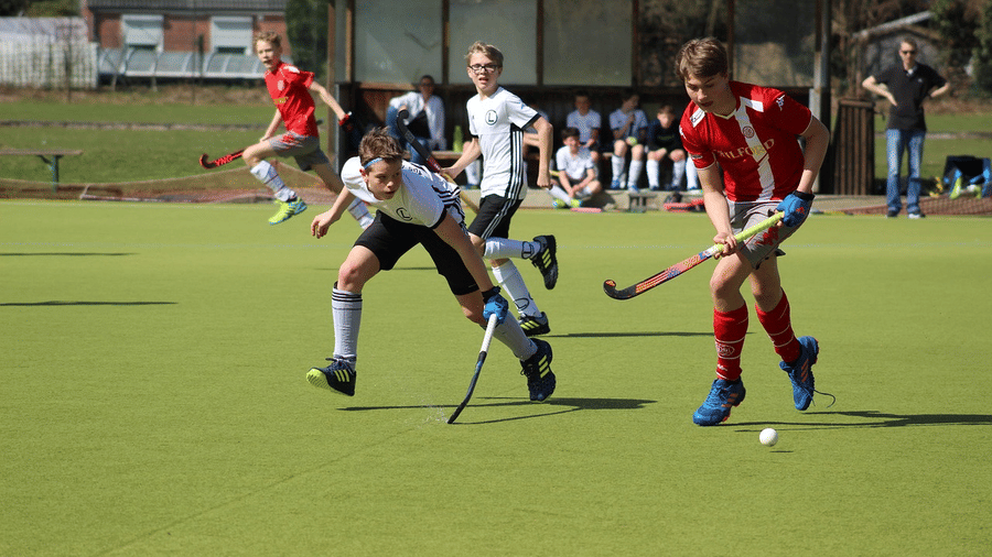 A field hockey match with players competing for the ball on a hockey field.