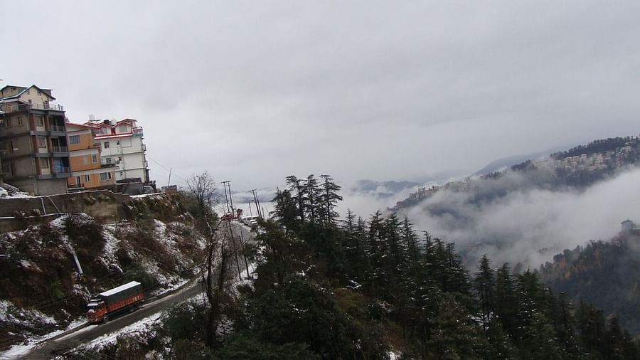 The aerial view of the mountain landscape covered in pine trees, buildings and clouds - The Orchid Hotel Shimla
