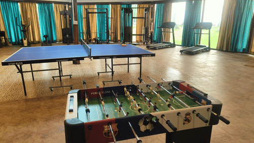 Indoor recreation area at Silver Sand Sea Princess Beach Resort, Port Blair featuring a foosball table, table tennis, and fitness equipment.