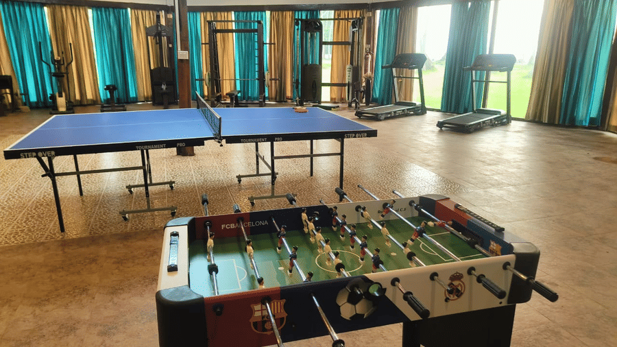 Indoor recreation area at Silver Sand Sea Princess Beach Resort, Port Blair featuring a foosball table, table tennis, and fitness equipment.