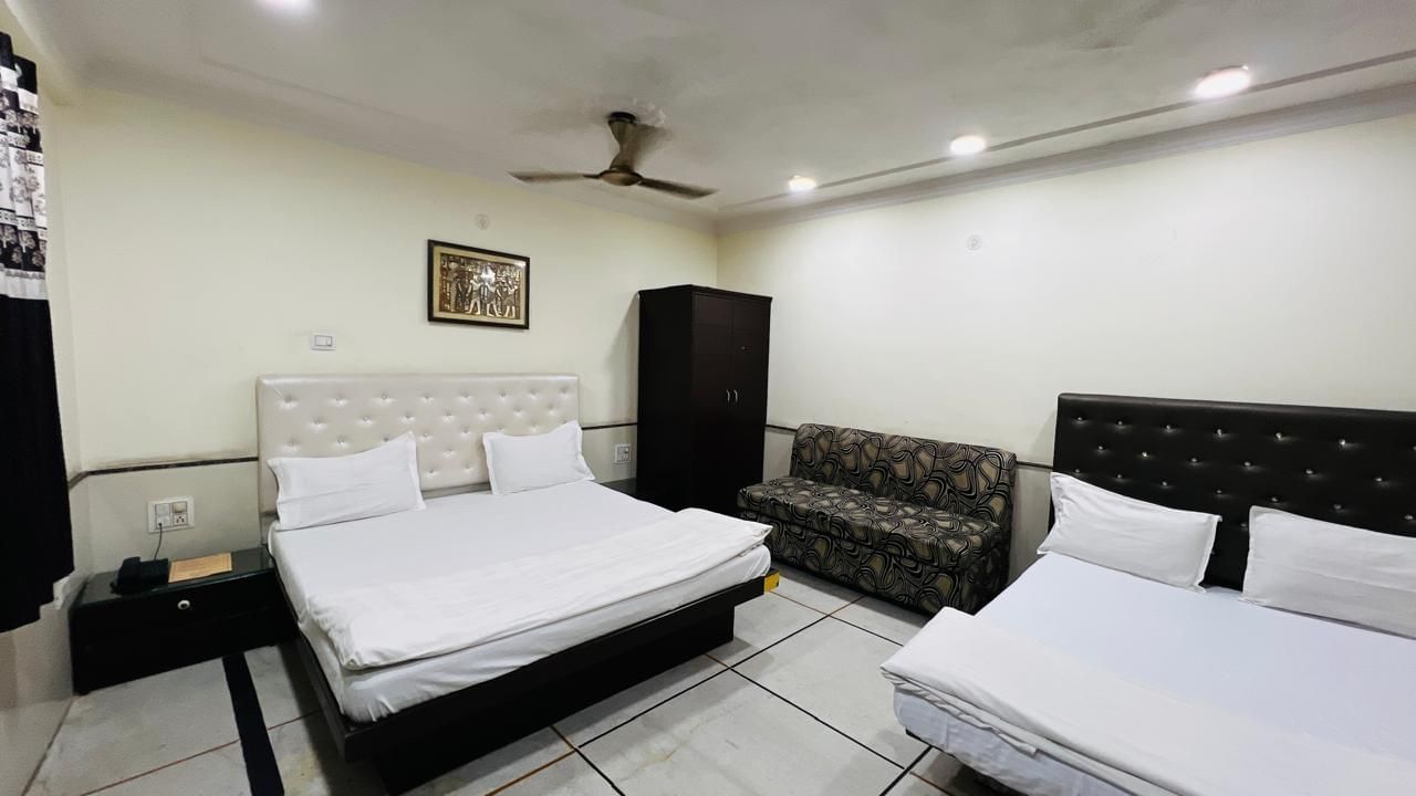 A family room at Ajay Guest House with multiple beds and a seating area, designed to accommodate families or groups comfortably.