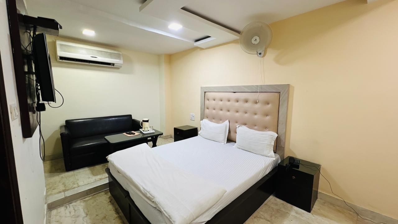 A cozy deluxe room featuring a comfortable bed with white linens and a light-colored headboard, perfect for a restful stay. | Deluxe Room | Ajay Guest House