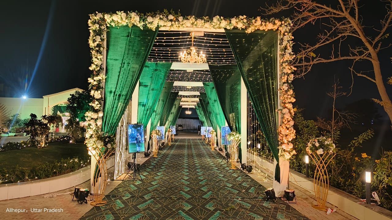Brij Eternity, Vrindava | A beautifully illuminated pathway with green and gold drapery leading to the wedding venue.