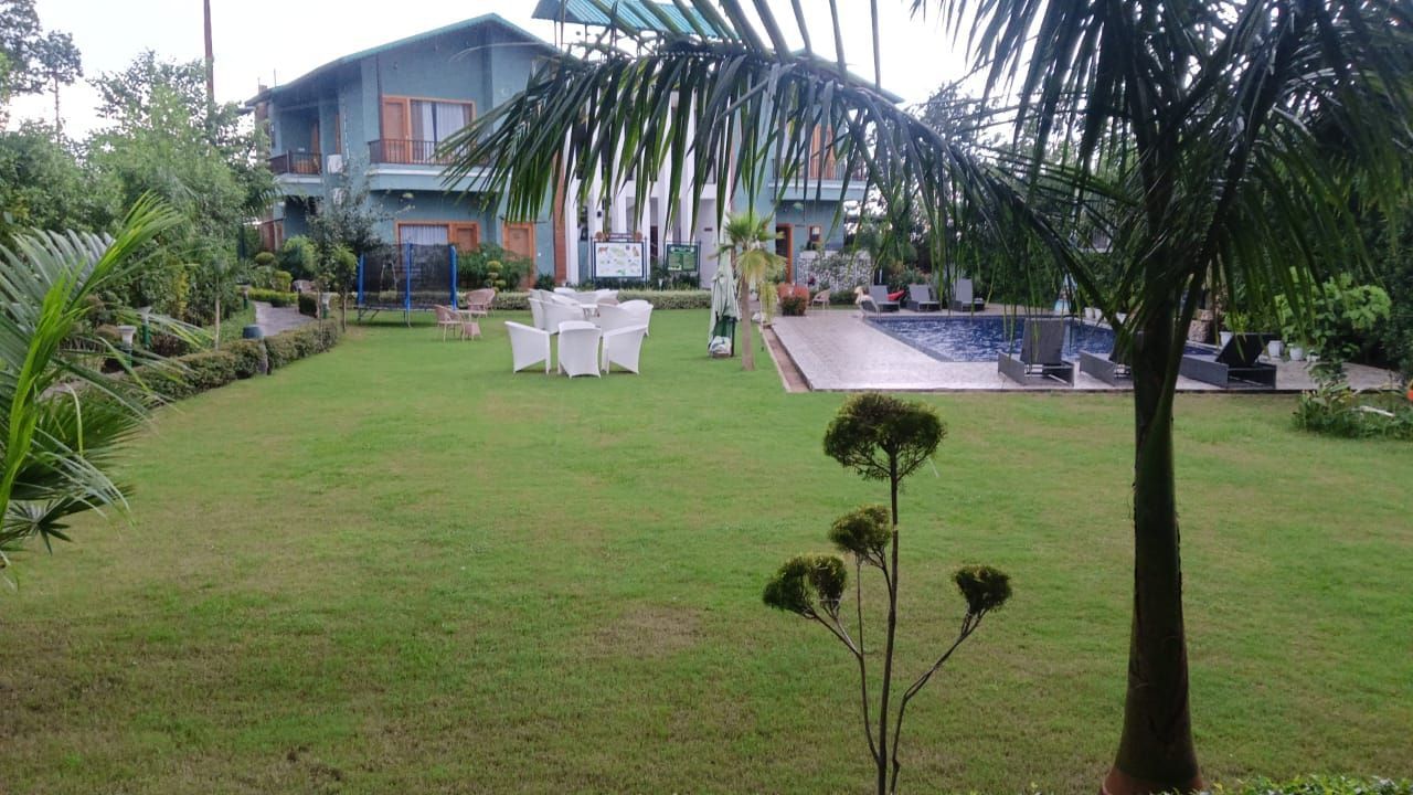 Full view of Lawn 1 featuring a well trimmed grassy lawn surrounded by trees and bushes at Corbett Nirvana Resort.