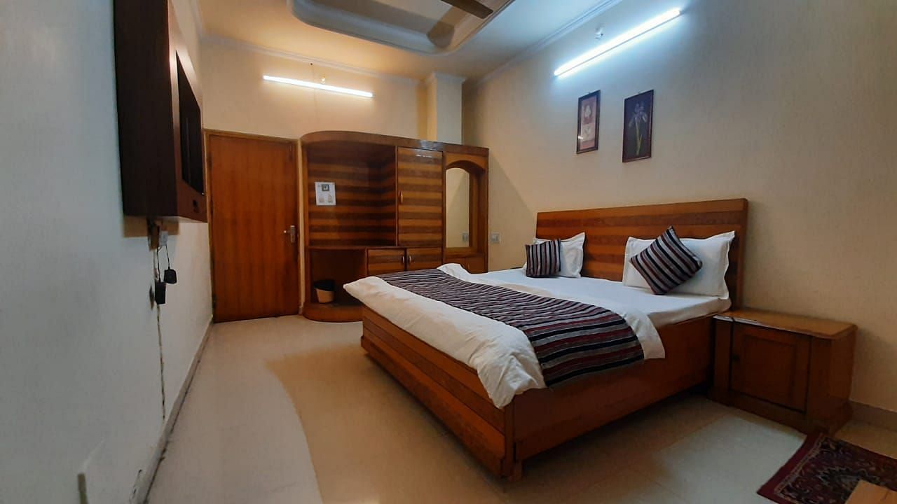 An image of our Semi Deluxe Room equipped with a queen size bed, a cupboard, and a wall-mounted television - Motel Divine International, Roorkee