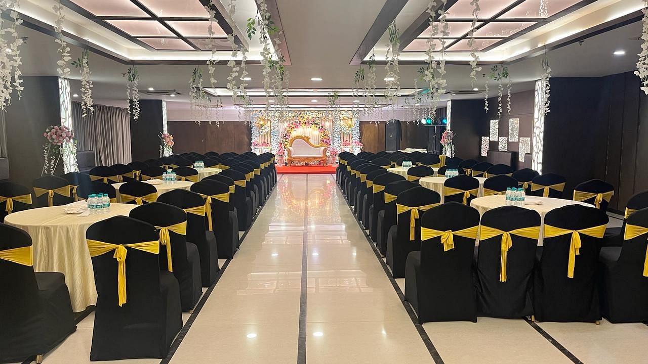 an image of the banquet hall with black chairs facing towards the stage | Yashshree Milestone, Siliguri