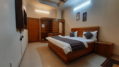 An image of our Semi Deluxe Room equipped with a queen size bed, a cupboard, and a wall-mounted television - Motel Divine International, Roorkee