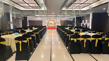 an image of the banquet hall with black chairs facing towards the stage | Yashshree Milestone, Siliguri