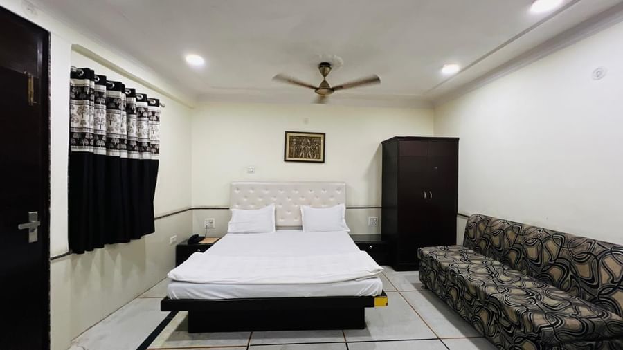 A spacious family room at Ajay Guest House featuring a large bed, a sofa, and traditional decor, offering a cozy ambiance.