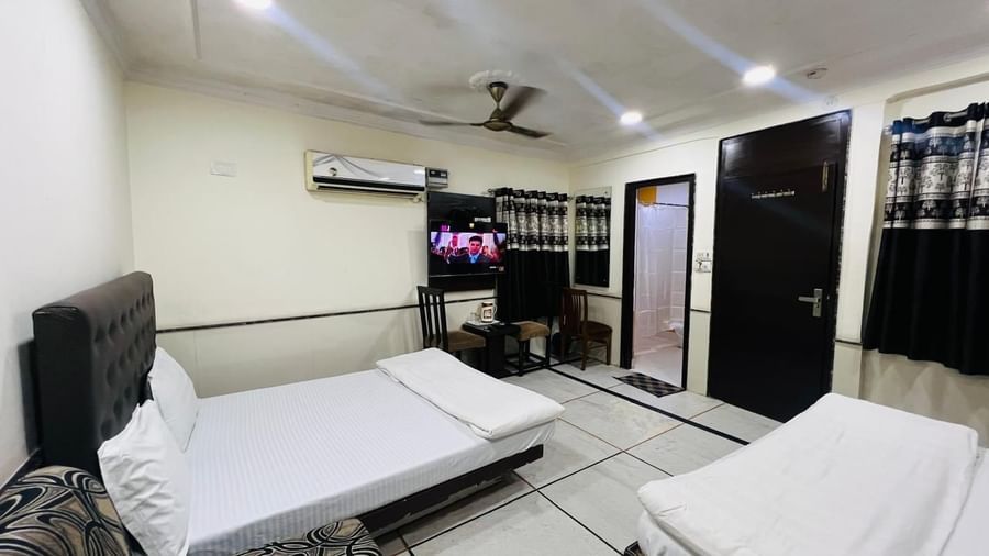 A family room at Ajay Guest House with two beds, a TV, and air conditioning, providing a comfortable space for multiple guests.
