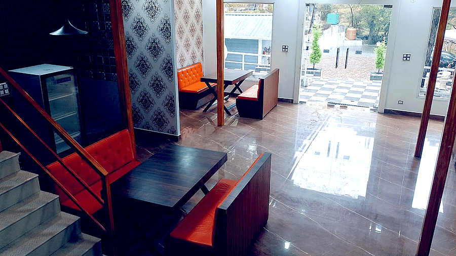 The interiors of the restaurant at DLS Nature Trinket Resort with red couches and tables.