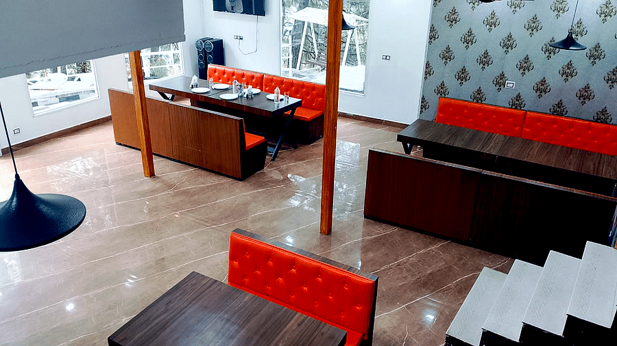 The interiors of the restaurant at DLS Nature Trinket Resort with red couches and tables.