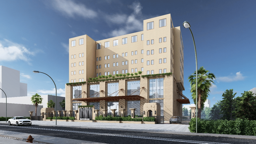 The facade of Essentia Luxury Hotel and Convention, Nagpur, featuring a multi-storey building surrounding by green bushes and trees and an empty road in the foreground.
