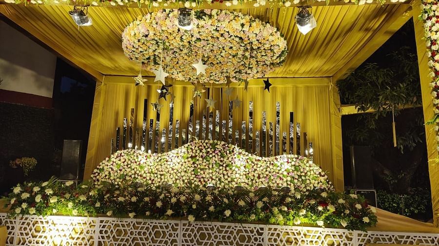 A lavishly decorated wedding stage with a large, ornate backdrop, a chandelier, and floral arrangements.