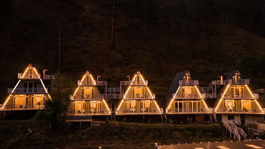 A nighttime view of four illuminated A-frame cottages, showcasing their distinctive architectural design.