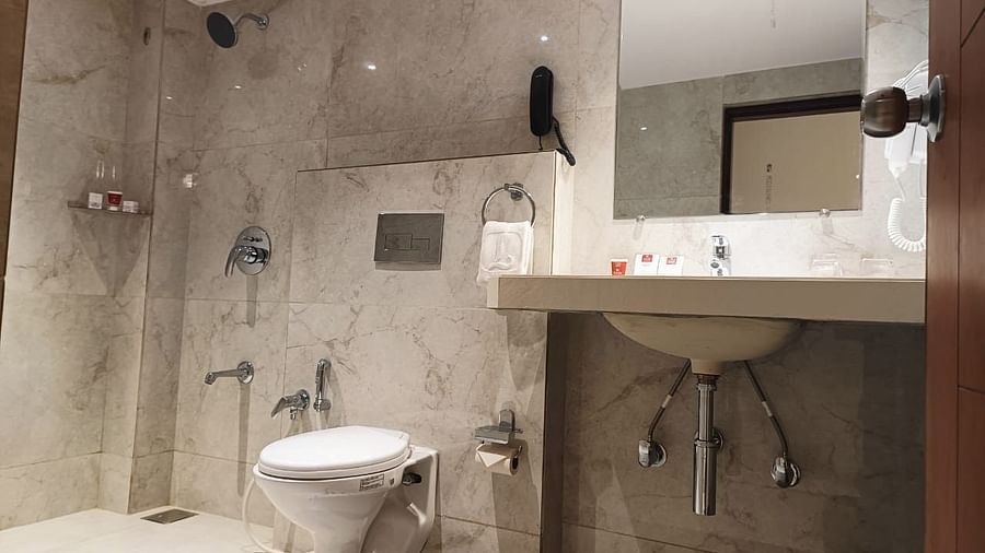 A modern hotel bathroom with a sink, toilet, and tiled shower area - Lords Eco Inn Dahej