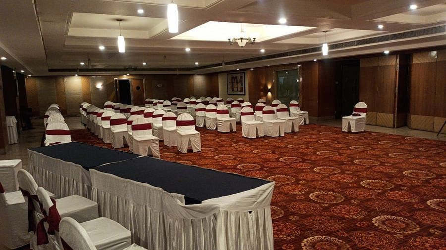 Large banquet hall with rows of chairs arranged, a carpeted floor, and lights on the ceiling, set up for a meeting or event - Lords Plaza Ankleshwar