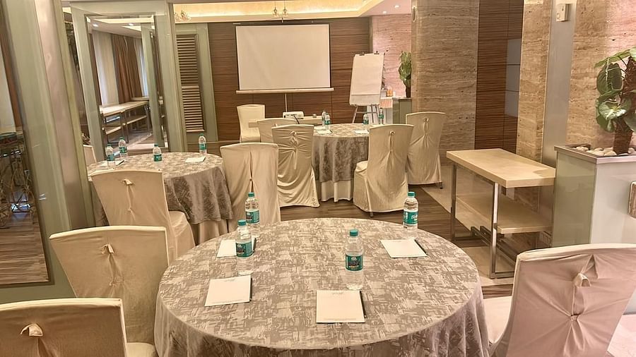  Round banquet tables with silver covers and chairs, ample seating area, projector and wooden flooring at Mirage Hotel, Mumbai.