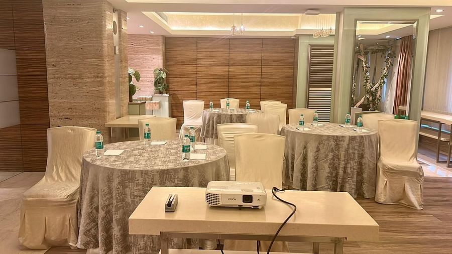 Conference-style setup with covered chairs and a central projector on a table at Mirage Hotel, Mumbai.